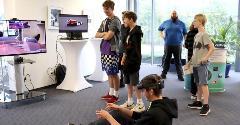 Teilnehmende Schüler probieren 3D-Brillen um damit einen Rennwagen zu fahren