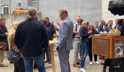 Personen aus verschiedenen Unternehmen beim gemeinsamen Stehfrühstück draußen und beim netzwerken